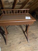 Front view of the wooden school master desk showing refinished surface, spindle backrest, and curved legs.