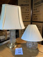 Photo of two glass and brass lamps with shades on wooden table, showing overall appearance.