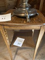 Side view of the vintage oak side table with metal lamp base on top and Lot 13 card on lower shelf.