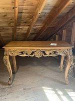 Full view of vintage wood long entry table showing carved apron and cabriole legs with gold artwork.