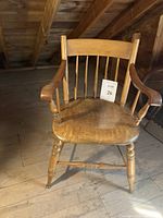Front and side view of a Windsor style wooden captain chair with smooth maple finish and turned legs.
