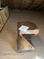 Side view of wooden twist stool showing the quarter twist design and solid wood construction on wooden floor.