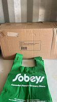 Cardboard box labeled for Sobeys reusable bags with one green bag displayed in front.