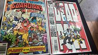 Both Guardians of the Galaxy and Deadpool comics in sealed packages shown side by side on table