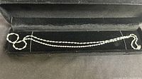 Silver twisted rope chain necklace displayed inside a black velvet jewelry box.