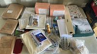 Top view of the lot showing multiple stationery and craft items including boxes, sewing spools, notepads, and pens.