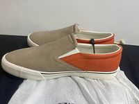 Side view of beige and orange casual slip-on Zara men's shoes resting on Zara dust bag.
