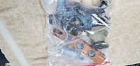 Photo showing clear plastic bag with multiple metal hardware pieces and a small wooden level