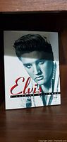 Front cover of Elvis: A Life's Pictures coffee table book featuring a black and white portrait of Elvis Presley with red and black text.