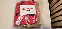Red State Farm shirt with Jake name tags folded and sealed in clear plastic packaging.