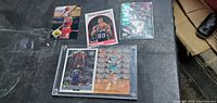 Top view of six assorted basketball cards on a black surface, including a Dave Robinson card and others.