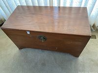 Top view of the wooden chest showing its rectangular shape, medium brown wooden surface with scratches