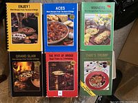 Front covers of six spiral-bound 'Best of Bridge' cookbooks arranged in two rows of three, showing the titles and cover images of food dishes.