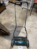 Photo showing the full view of green Yardworks manual push lawn mower with metal handle and grass cutting blades.