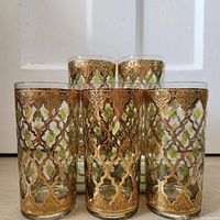 Five Culver Valencia highball glasses featuring an ornate 22K gold overlay lattice design, positioned with three in front and two behind.