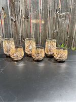 Six vintage woodcock bird glasses on black surface, arranged with taller glasses at back and shorter glasses in front.