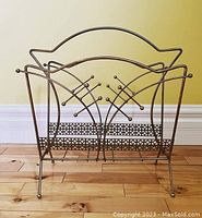 Front view of the atomic style metal magazine rack with geometric pattern base and ball-tipped rods.