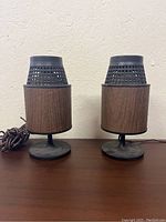 Front view of pair of vintage atomic style speakers with wood grain bodies and black tulip bases on wooden surface.