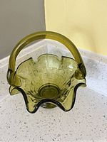Photo showing the top and interior view of the avocado green glass basket, highlighting the ruffled edge and basket weave texture.