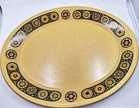 Oval Kilncraft platter showing Bacchus pattern around border in yellow, black, and brown.