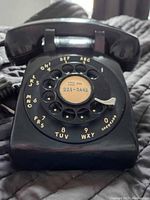 Black Northern Electric rotary phone from above showing dial and handset position, scratches visible.