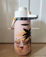 Full view of the air pot showing the Miami sunset scene with palm trees and sailboats, and the white top with spout and lever.