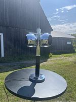 Trio Spaceage eyeball table lamp shown from side angle on black round table with a rural barn background.