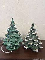 Two vintage ceramic Christmas trees side by side showing full height and condition differences.