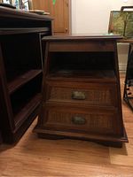 Full front view of the pyramid style solid wood end table showing two drawers with woven style drawer faces and metal handles, and an open shelf below the tabletop.