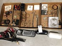 Wide view of all costume jewelry pieces including bracelets, necklaces, belts, sunglasses, and a hair curling iron with cases.