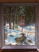Framed oil painting depicting a snow-covered forest landscape with trees and rocks.