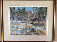 Framed oil painting showing a nature scene with water and trees, signed by artist.