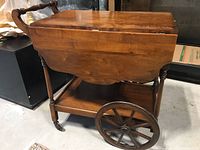 Side angle showing the wood finish, turned handle, and drop sides of the tea cart.