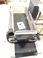 Full treadmill view showing running belt, frame, and manual with Allen key placed on belt.