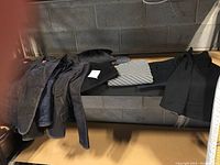 Photo showing multiple jackets, including a corduroy jacket and others in dark colors, hanging over a bench.