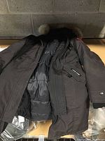 Coat laid flat showing exterior shell and down puffer interior