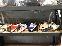 Full view of six pairs of women's heeled shoes on shelf including strappy, smooth leather, and woven styles with shoe boxes behind.