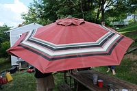 Full view of 8ft diameter red patio umbrella with striped pattern open outdoors