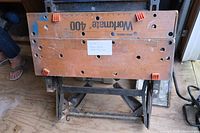 Top down photo of Black & Decker Workmate 400 workbench showing wooden top surface with orange plastic clamps and visible signs of use.