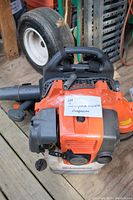 Top view showing orange engine housing, handle, starter rope and attached identification tag