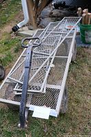 Metal garden cart with mesh platform and handle visible from the top with some wood and garden supplies in the background.