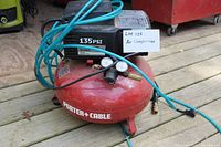 Side view of red Porter Cable air compressor with black top, blue air hose coiled on, gauges, and power cord.