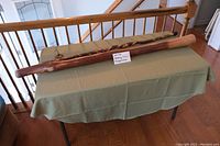 Photo of two items on a table: a long wooden walking stick and a wooden didgeridoo, showing overall size and shape.