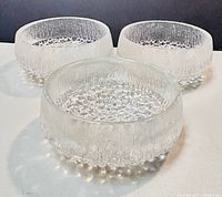Photo showing three clear textured glass bowls from an elevated angle on white surface, displaying the icy textured design and shape.