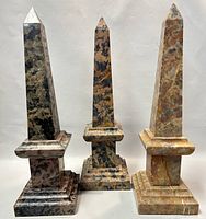 Front view of the three vintage Italian marble obelisks showing varied marble colors and natural veining on stepped bases and pointed tops.