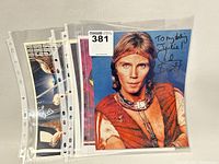 Set of four signed celebrity promotional photos displayed in clear sleeves, showing detailed autographs and inscriptions.