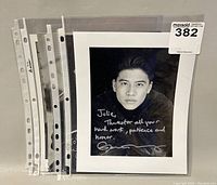 Four black and white signed celebrity promotional photos stacked in protective sleeves.