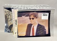 Four signed celebrity promotional photos from Babylon 5 in plastic sleeves, laid flat on a surface.