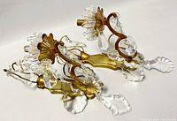 Pair of brass sconces laying side by side showing overall shape, brass finish, and hanging crystal drops.