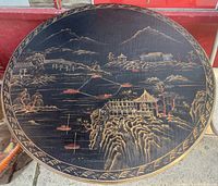 Top view of the round table showing intricate hand painted Chinese landscape scene with cliffs, pagodas and boats.